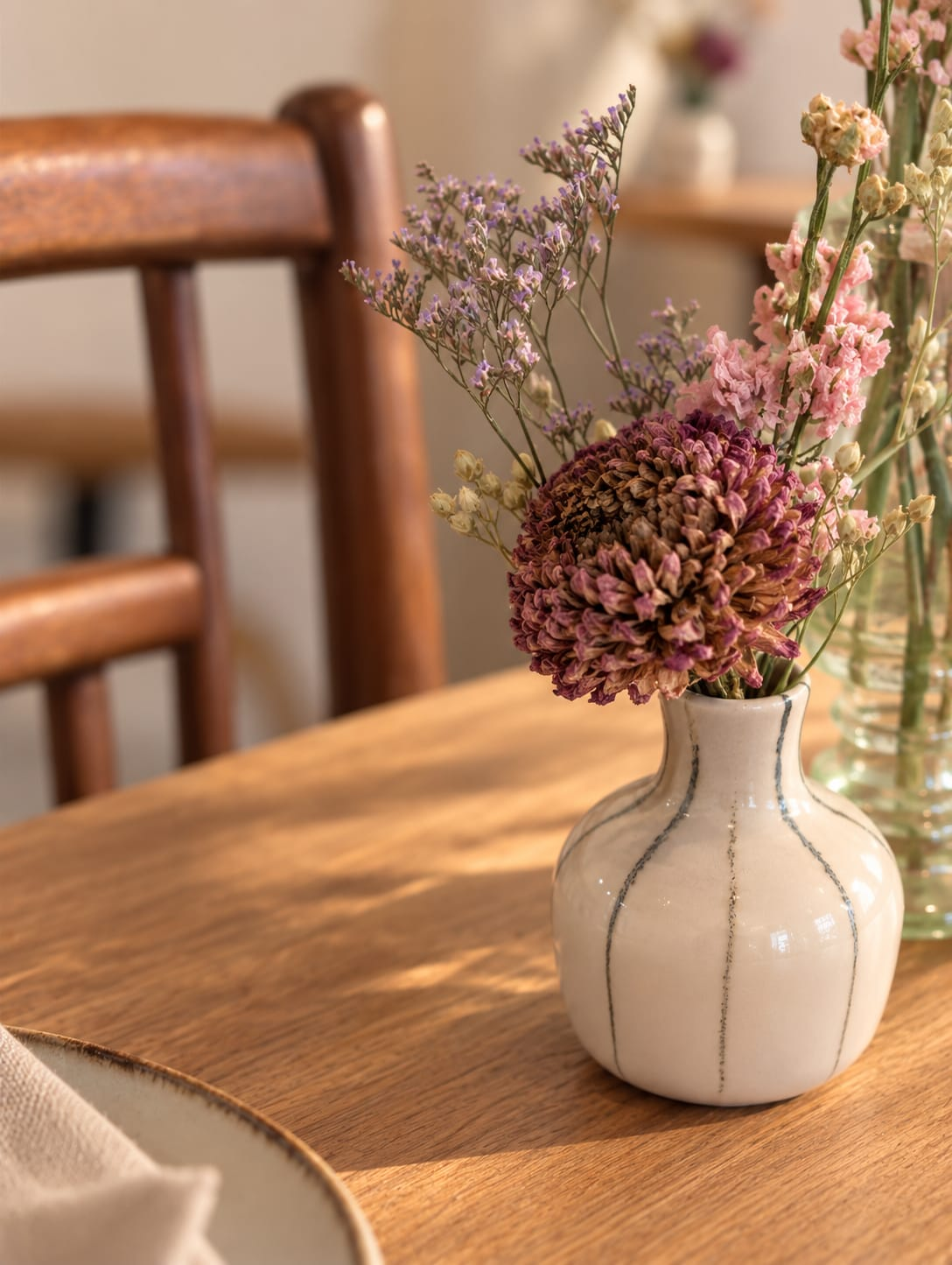 Un bouquet de fleurs dans un vase en céramique, sur une table en bois baignée de soleil